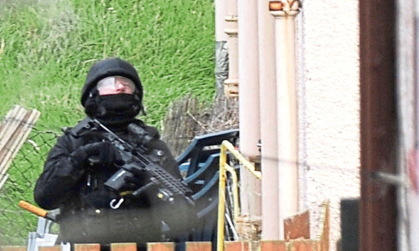 An armed police officer at the rear of a house in Kirktoun Street, Ballingry, Fife.