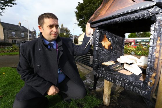 Local councillor David Graham surveys the damage done after the library was destroyed.