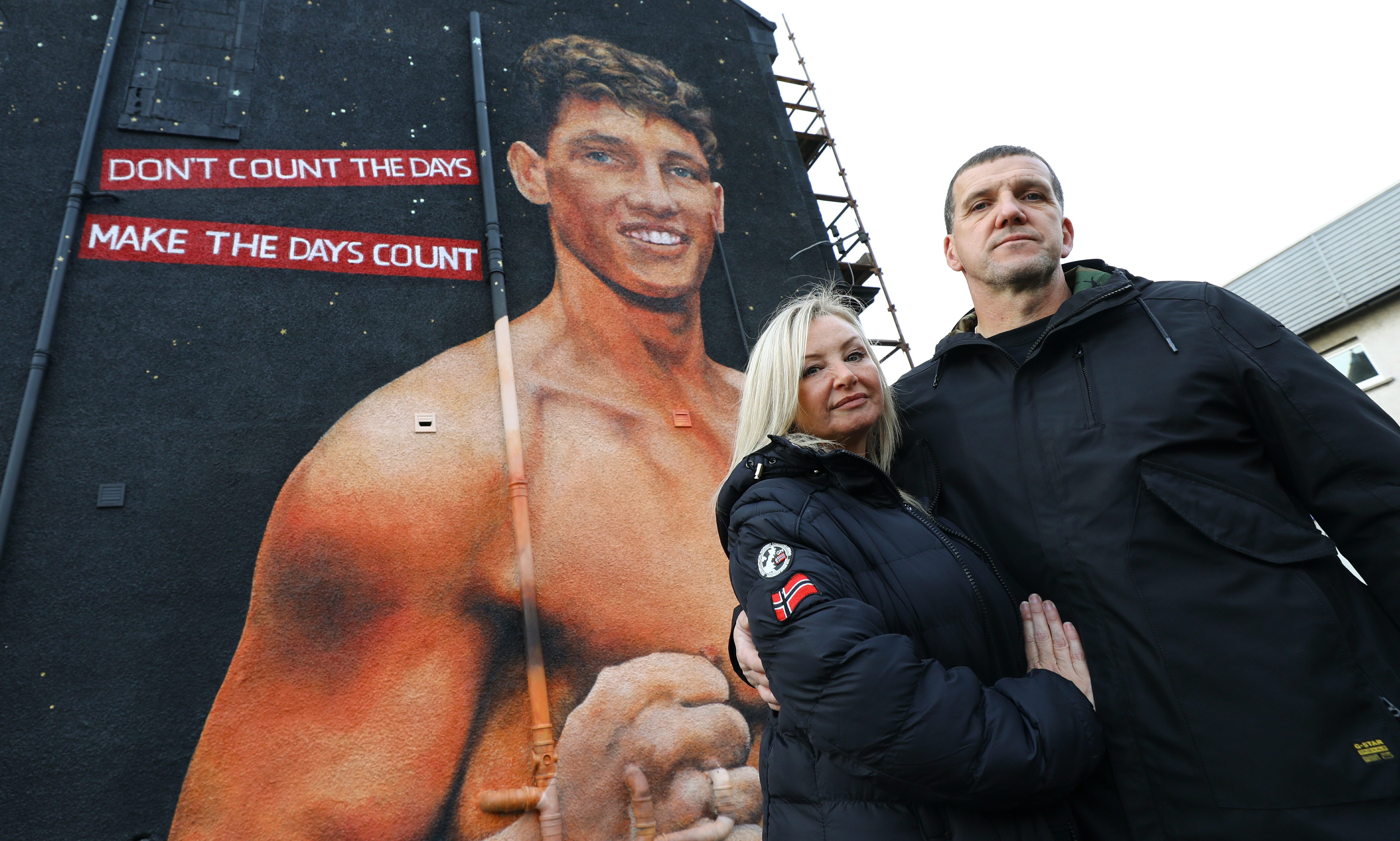 Connor Law's parents Kaye and Gary Law beside the mural of their son.