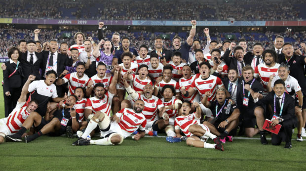Japan players and management celebrate after defeating Scotland.