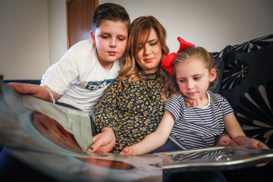 Zach Kyles, 11, Nadia Wright, 32 and Sofia Neish, 4, looking at pictures of son Brandon Kyles.