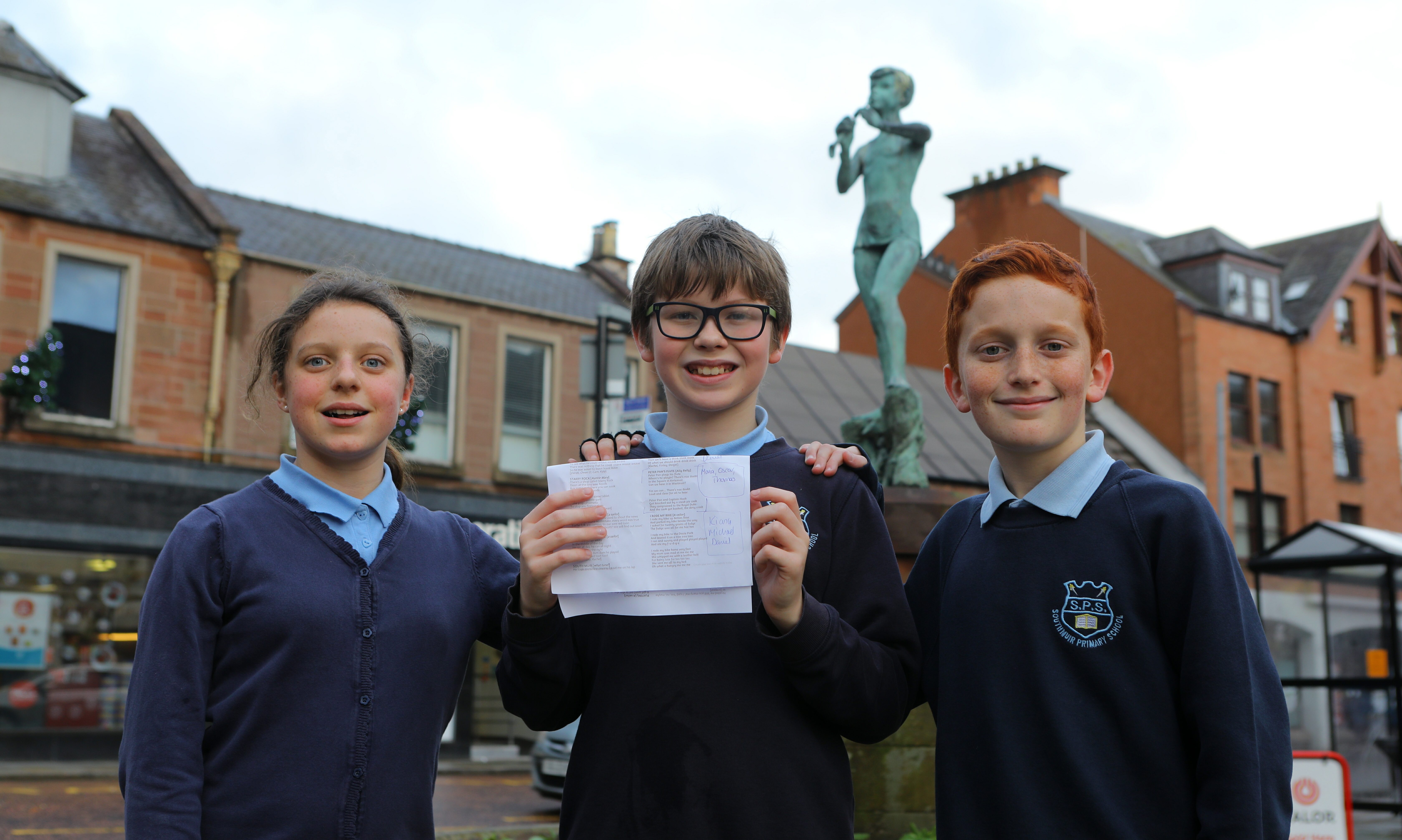 Beside the Peter Pan statue in Kirriemuir, Maia Valentine, Thomas Watson and Oscar Grey from Southmuir Primary School, who wrote a poem about Peter Pan.