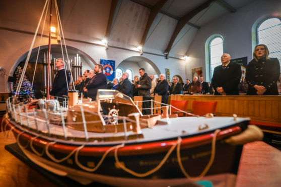Members of the RNLI squad in the front rows of the church with a model of the Mona Lifeboat