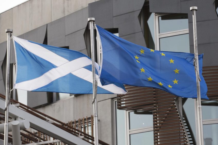 Photo shows the Scottish and European flags outside the Scottish Parliament building in Edinburgh.