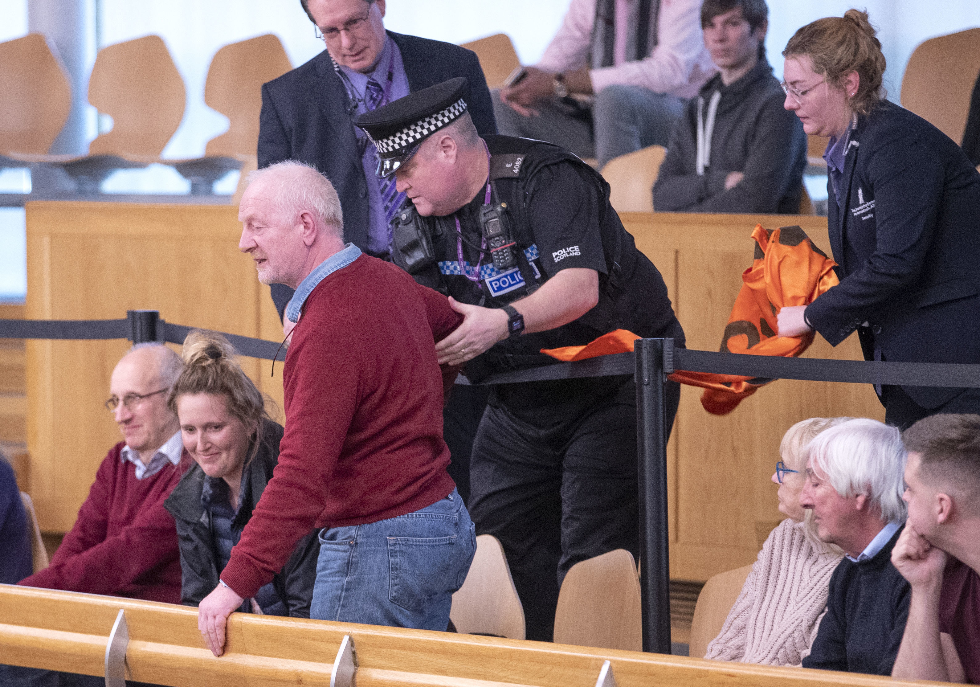 A climate change protester is removed by police from the public gallery during First Minister's Questions at the Scottish Parliament in Edinburgh