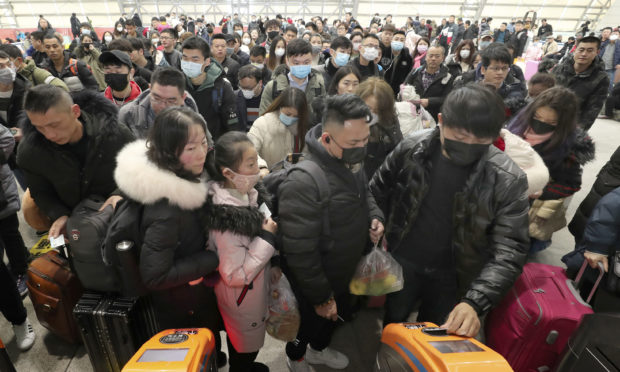 Travellers wear face masks as they line up at turnstiles at a train station in Nantong, eastern China, at the start of the coronavirus outbreak in January 2020.