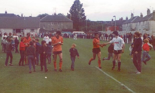 David Narey (centre) and Eamonn Bannon sign autographs for young fans following a match between St Andrews United and Dundee United at Recreation Park while Stuart Beedie shakes hands with an opponent. 30 July 1985. The game finished 5-1 for the tangerines.