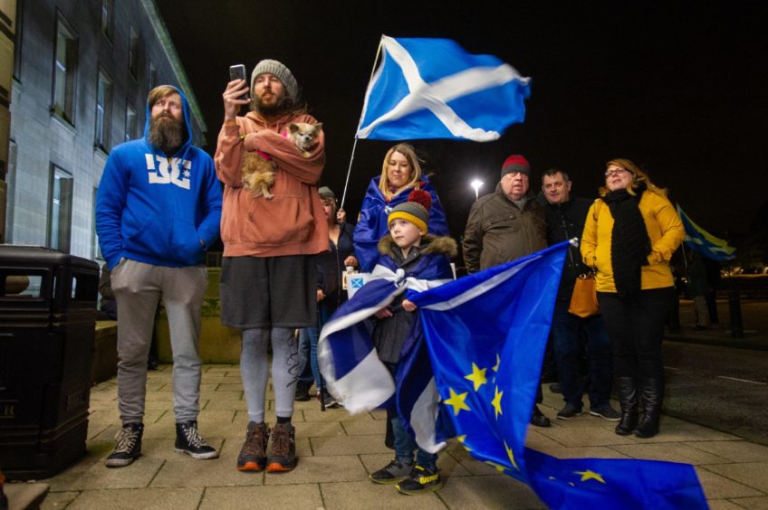 photo shows a small group of people, one holding a Scottish saltire, another the EU flag.