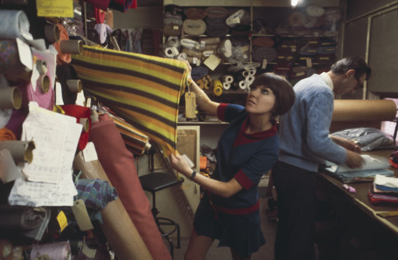 British fashion designer Mary Quant pictured selecting rolls of fabric from a fabric store and warehouse in London to create samples for a future collection in 1967.