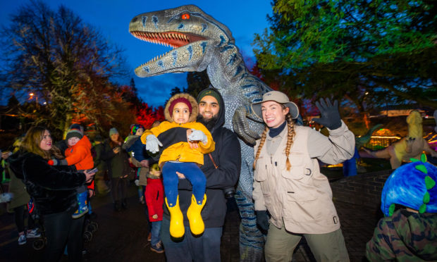 Ifran Ali and daughter Saarah Ali (aged 3, correct spelling) from Perth get up close to one of the dinosaurs Ritchie the Raptor alongside Ranger Georga.