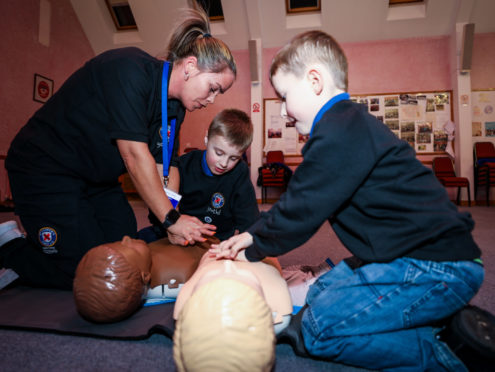 Harley and Fraser practice CPR instructed by Kelly.