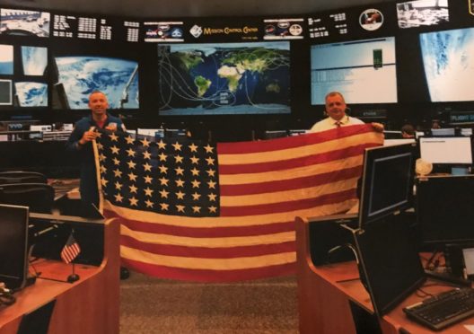 Astronaut Rudy Bresnick (left) and a member of NASA mission control with the Glamis flag in the operations hub.