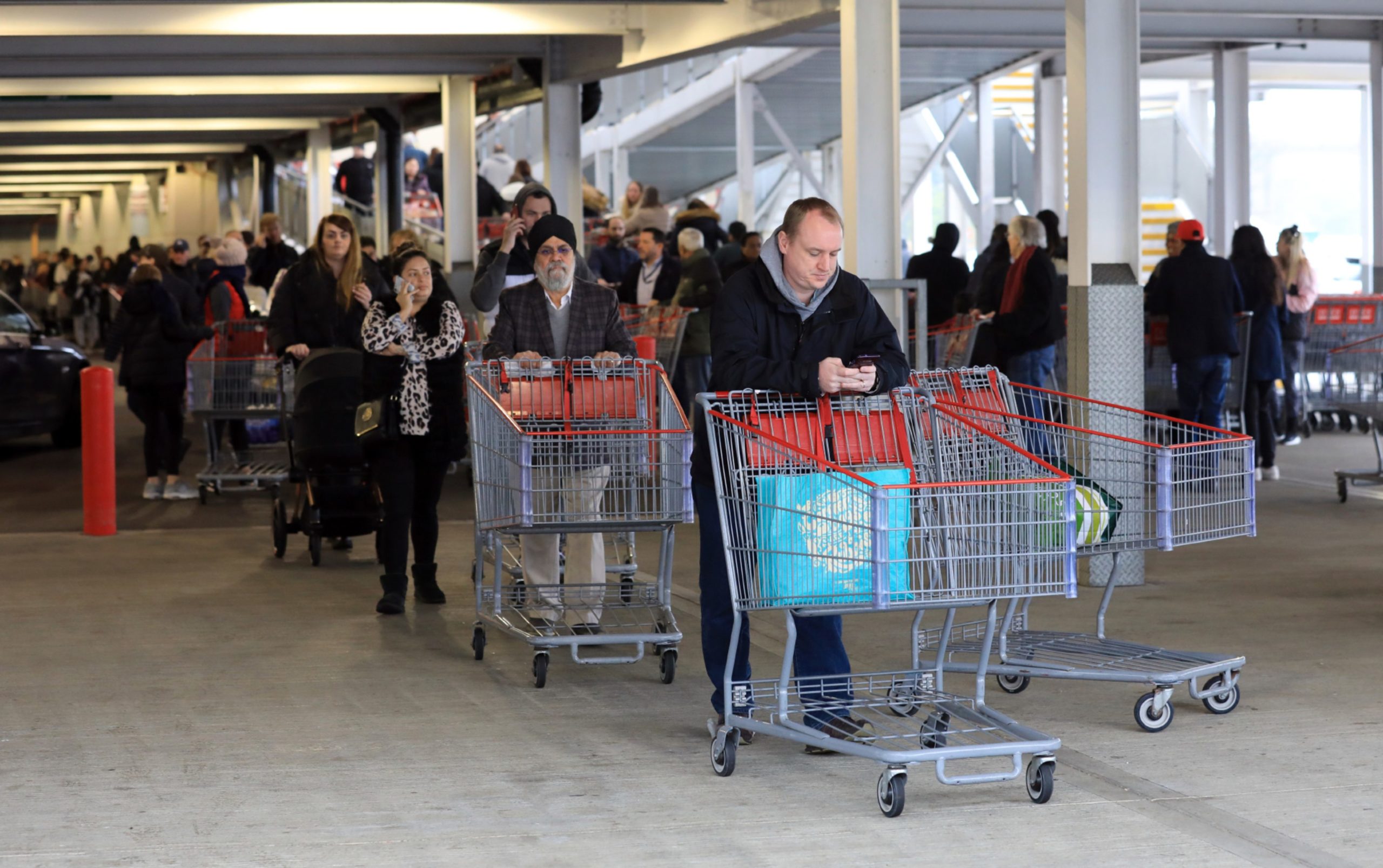 Coronavirus panic buying - hundreds of customers queue for over an hour with empty trollies zig-zaging through the car park at Costco wholesale warehouse, Sunbury-on-Thames