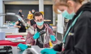 Royal Mint employees assemble full face visors in the cafe inside the Royal Mint Experience.