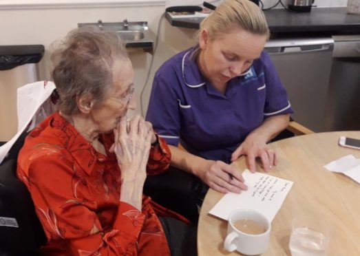 Carol Stillie, Activities Coordinator at Balhousie Rumbling Bridge helping resident Ursula Crichton write a letter.