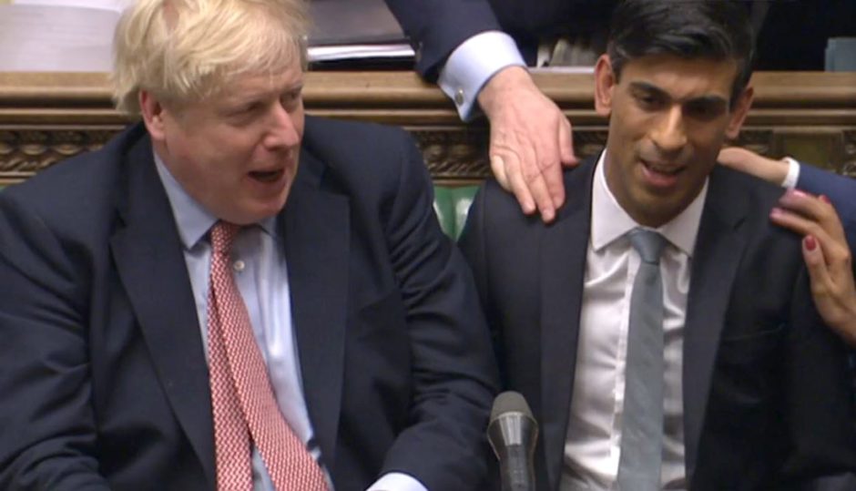 Chancellor Rishi Sunak (right) sits down after delivering his Budget in the House of Commons.