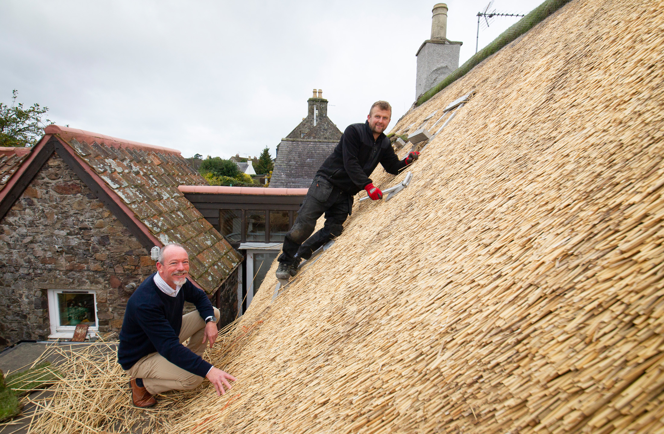 Fife Conservation Officer Matthew Price with thatcher Tomasz Obara at work on a thatched roof on Bow Road, Auchtermuchty.