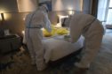 Workers in protective suits collect COVID-19 samples to test at a quarantine hotel in Wuhan in central China's Hubei province