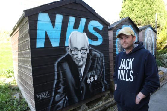 Symon beside his tribute to fundraiser Captain Tom Moore, on the sheds in Ellengowan Drive.