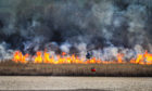A helicopter is used to dump vast amounts of water onto the flames destroying the reed beds near Errol in Perthshire.