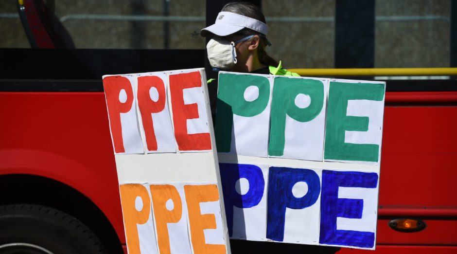 A demonstrator holds signs saying PPE outside St Thomas' Hospital in central London, where Prime Minister Boris Johnson was treated for coronavirus.