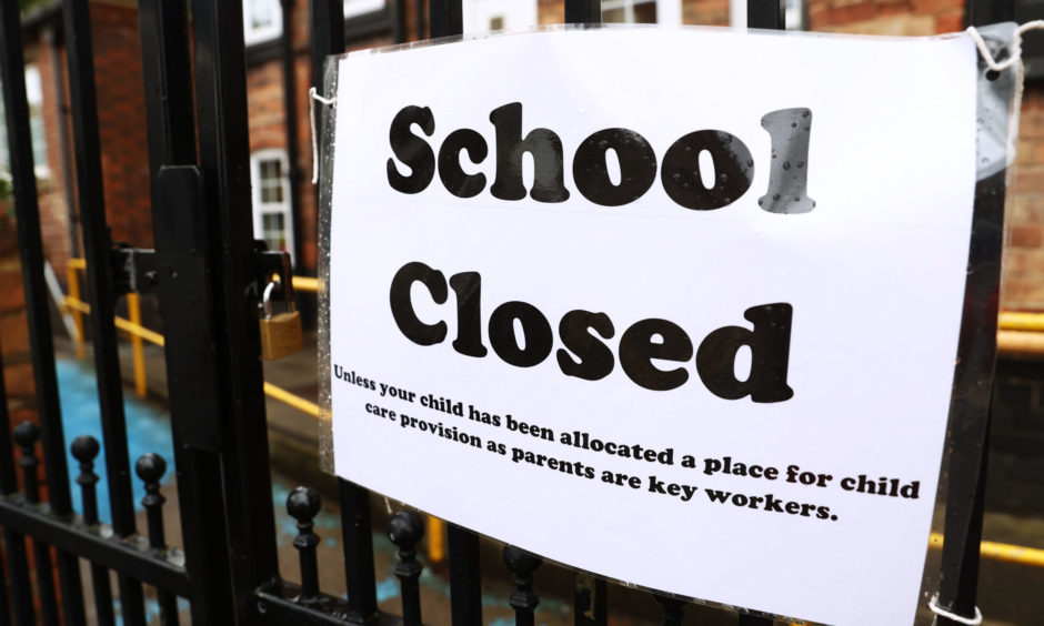 photo shows a sign on railings which reads 'School closed, unless your child has been allocated a place for child care provision as parents are key workers'.