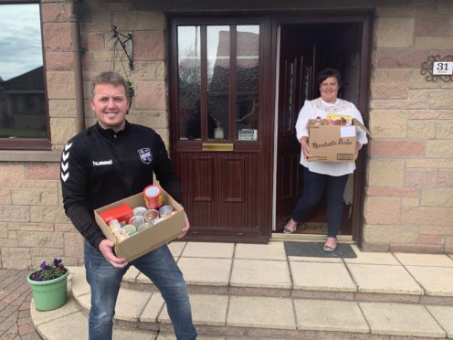 Peter Davidson collecting a "contactless" food package from Brenda Petrie.