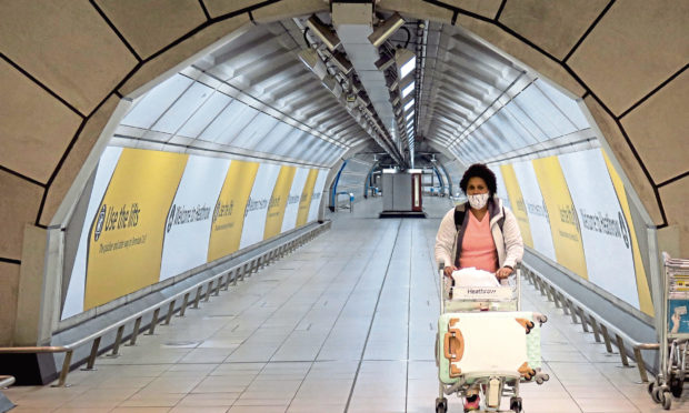 A passenger wearing a face mask is seen at Heathrow Airport in London.