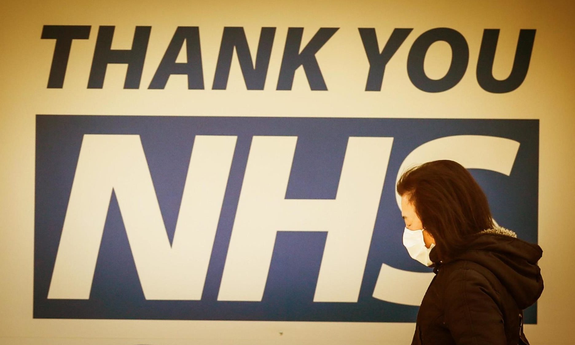 A woman walks past a sign thanking NHS workers.