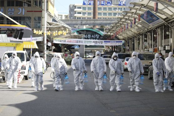 Workers wearing protective gear spray disinfectant as a precaution against the coronavirus at a market in Daegu, South Korea, which has been widely praised for its response to the coronavirus outbreak.
