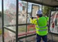 A council workman hard at work removing the graffiti from a bus shelter.