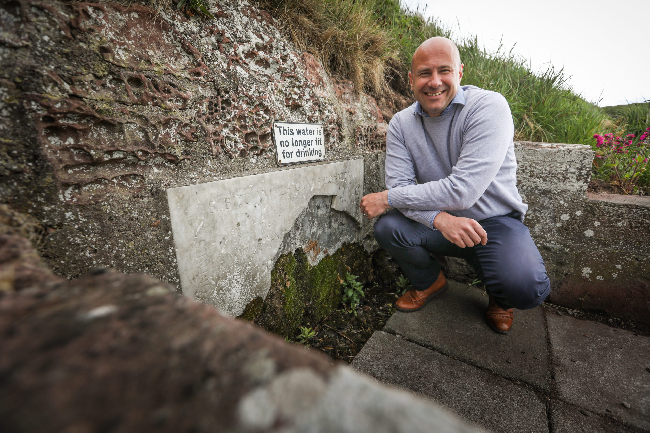 Councillor Wann next to the remains of St Ninian's well.  Mhairi Edwards/DCT Media