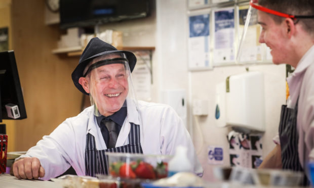 David McNee, a butcher from Hunters wears a facemask while he serves customers.