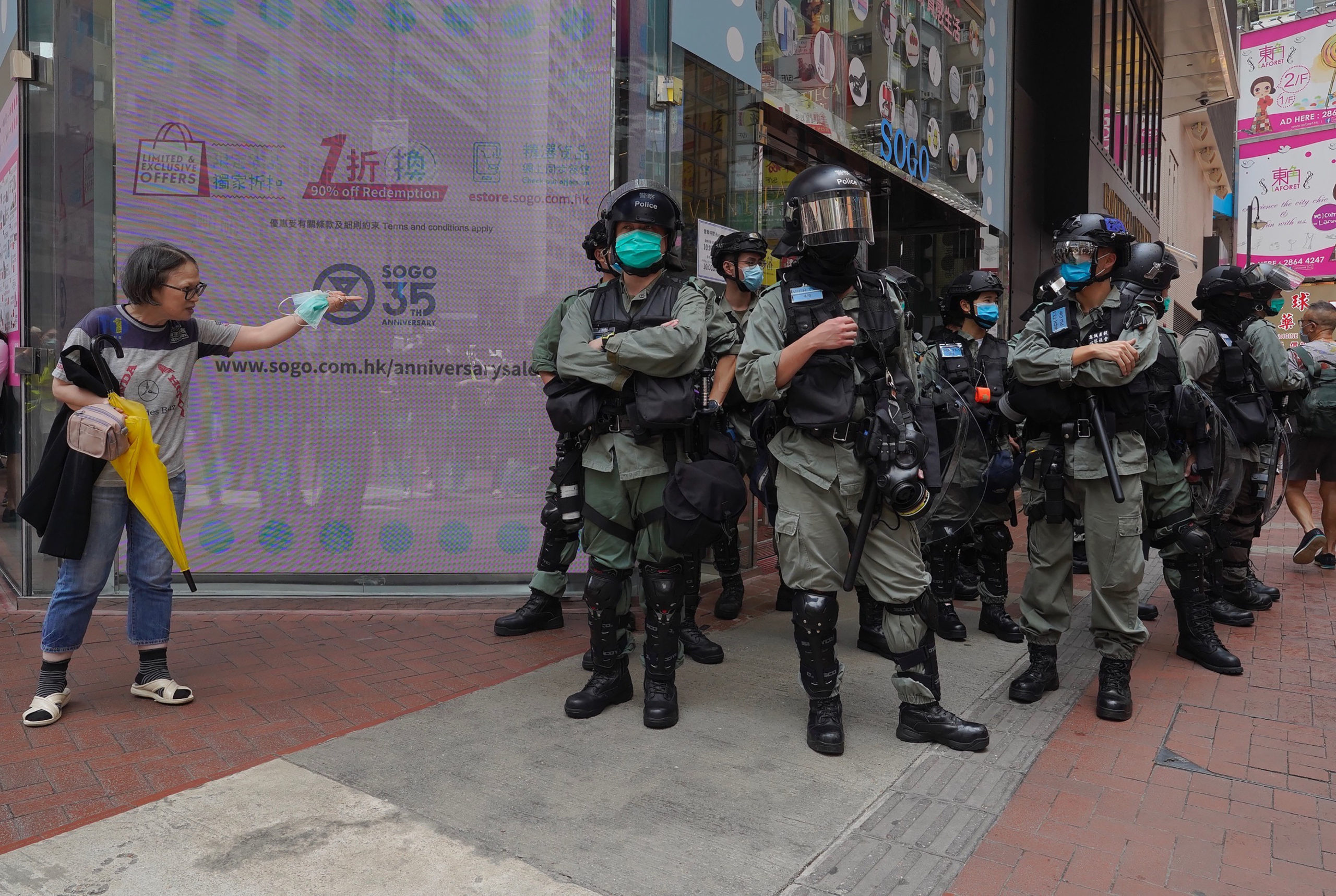 Riot police standing guard as a woman tries to cross the street in the Central district of Hong Kong.
