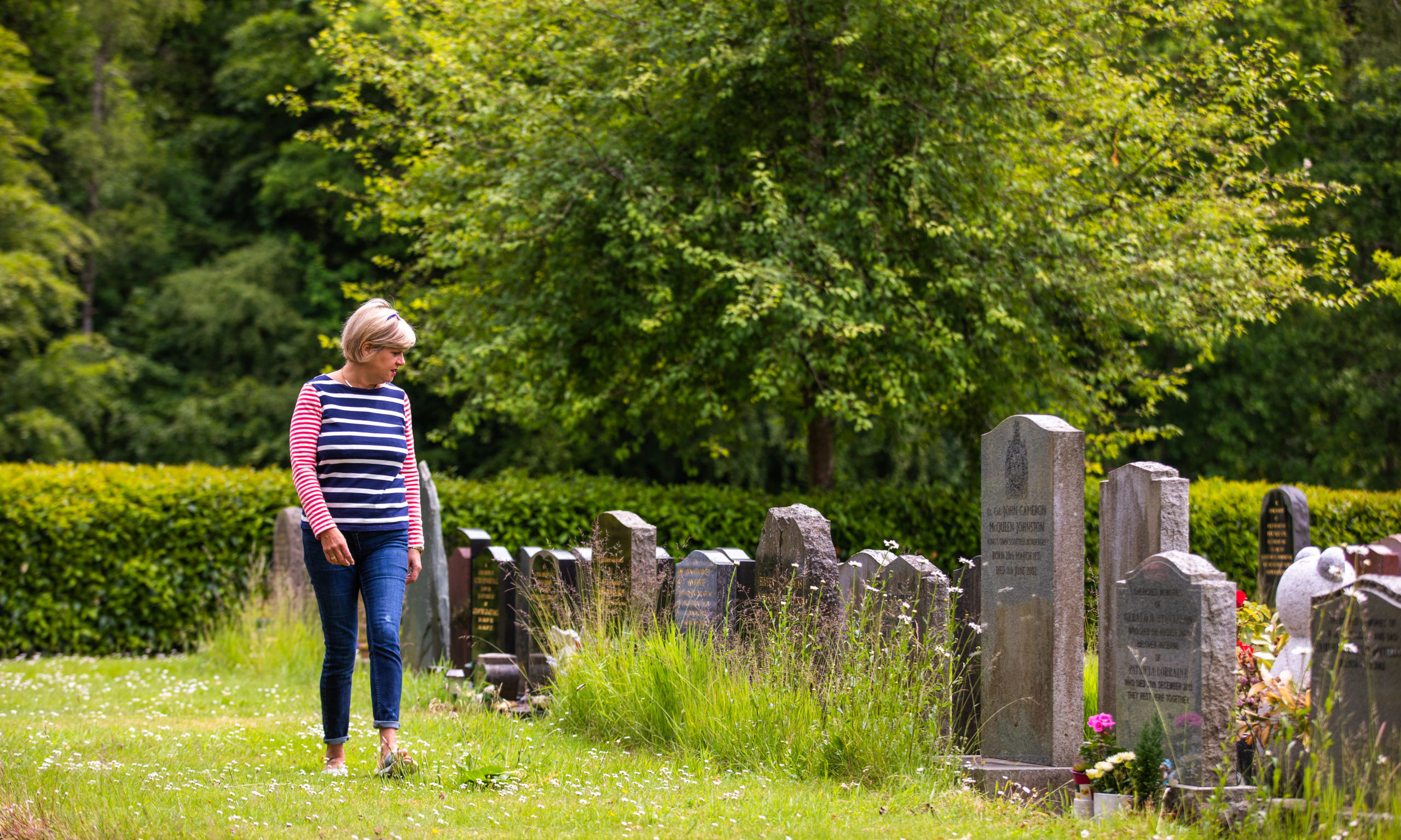 Gillian Brock at Comrie Cemetery where gravestones are obscured by weeds