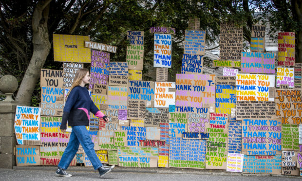 Hermione Wilson walks past a new artwork at Jupiter Artland, Edinburgh, created as a tribute to the NHS titled "A Thousand Thank Yous" originally devised by the late Allan Kaprow which consists of colourful painted messages on cardboard and has been directed remotely by London-based artist Peter Liversidge. PA Photo. Picture date: Monday June 8, 2020. The Jupiter Artland sculpture park recently re-opened to local members as Scotland continues in phase one of the Scottish Government's plan for gradually lifting lockdown. See PA story HEALTH Coronavirus. Photo credit should read: Jane Barlow/PA Wire