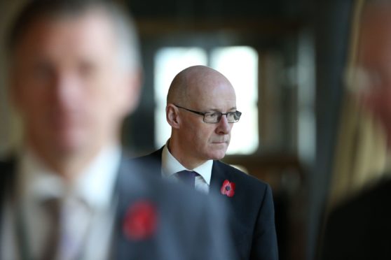 Education secretary John Swinney makes his way to the debating chamber to deliver his statement.