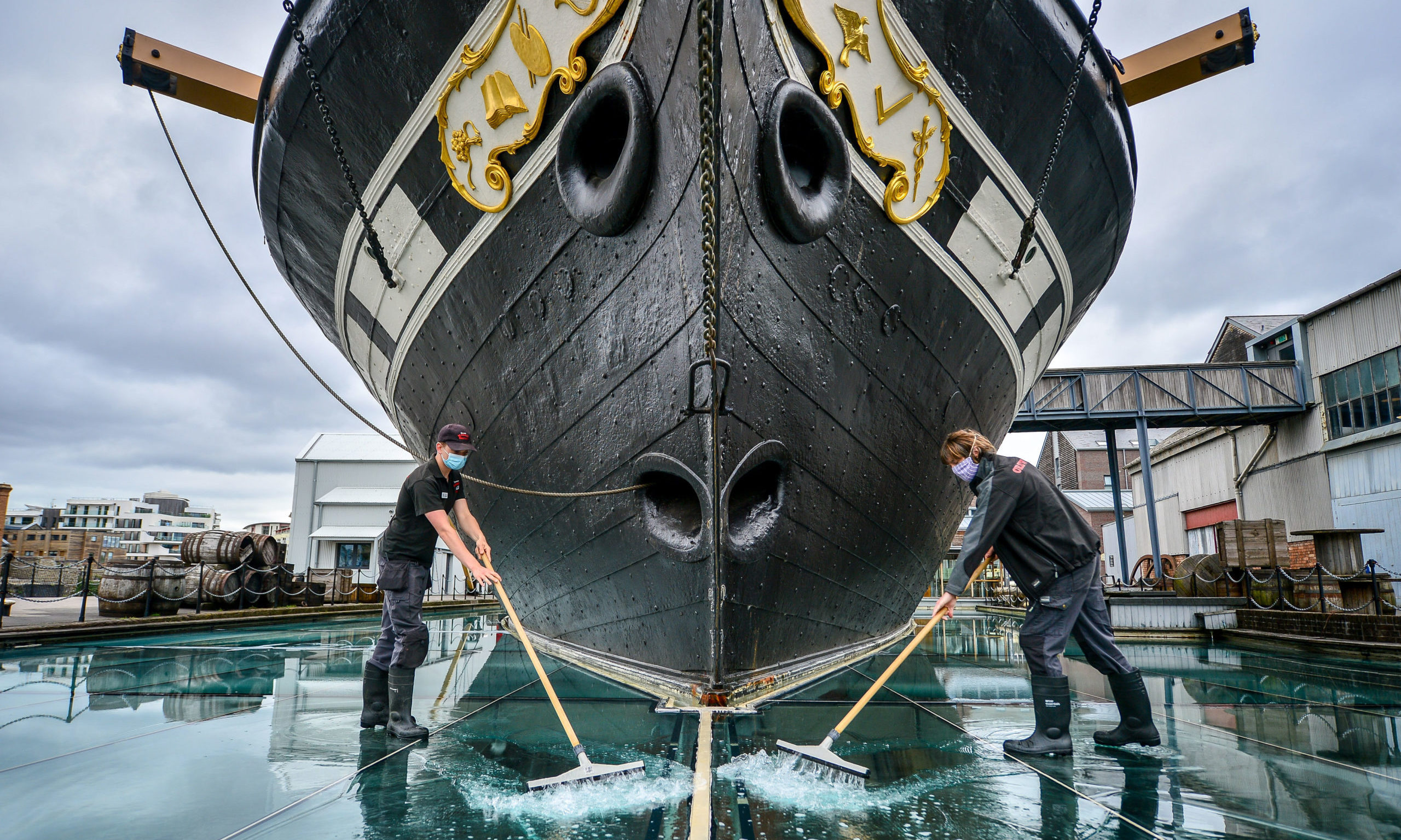 Technical services staff clean the surface of the glass sea, which is a series of glass plates surrounding Brunell's SS Great Britain and filled with water to create a sea effect, as the attraction reopens on Saturday, July 18, marking the 50th anniversary of the ships return back home to Bristol, after the lifting of further coronavirus lockdown restrictions in England. PA Photo. Picture date: Thursday July 16, 2020. See PA story HEALTH Coronavirus. Photo credit should read: Ben Birchall/PA Wire