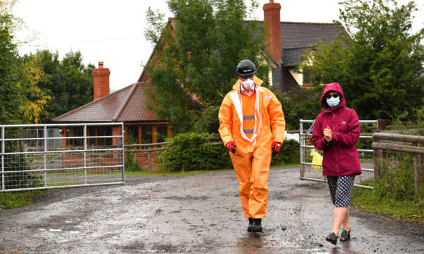 Karen Wright (left), Director of Public Health for Herefordshire CCG, sanitising before opening a gate to give a press statement outside Rook Row Farm in Mathon, near Malvern, Herefordshire, where there have been more than 90 positive cases of coronavirus confirmed.