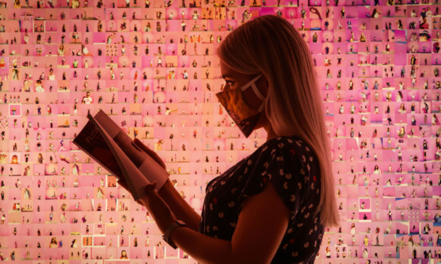 A visitor reads a program in front of a work titled 'Murmurations #23: 10,000 selfies (with a pink wall in Los Angeles)' by artist Stephanie Potter Corwin, that forms part of the Aesthetica Art Prize exhibition on show at York Art Gallery in Yorkshire. PA Photo. Picture date: Thursday August 13, 2020. Following reopening the exhibition is free to visit, with the gallery hoping that by removing admission charges there will be a higher number and increased diversity of visitors. The Aesthetica Art Prize is a celebration of contemporary art. The annual prize, now in its 13th year, provides a platform for both established and emerging practitioners from across the world.Photo credit should read: Danny Lawson/PA Wire