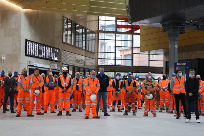 Rail staff stand in Glasgow Queen Street Station in memory of the Stonehaven rail tragedy victims.