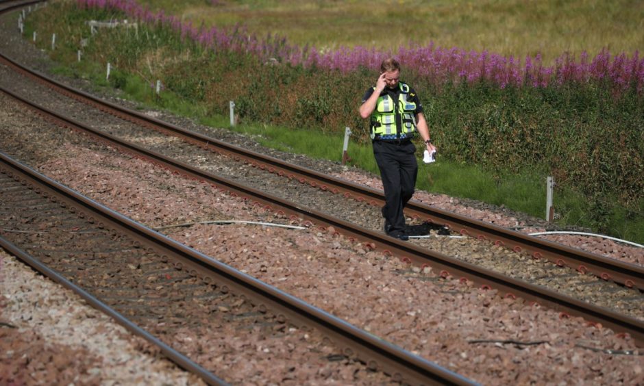 A police officer walks along the tracks at Carmont crossing on the train of the tragedy.