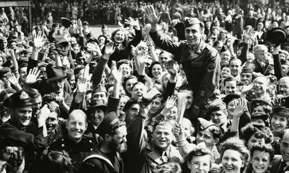 A jubilant crowd celebrates on hearing of the Japanese surrender on VJ Day in 1945, a date referenced by the first minister.