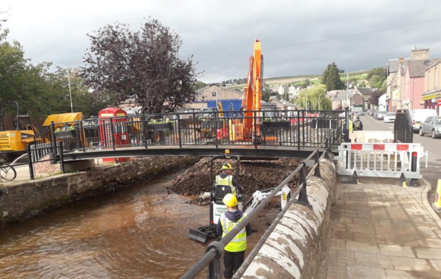 Workers clear debris from Alyth Burn in the town centre.