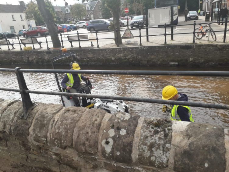 Workers clear debris from Alyth Burn in the town centre.