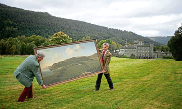 Staff members from Bonhams hold the painting Taymouth Castle and Estate including Loch Tay from the South, by the British artist John Sanger, on the hillside above Taymouth Castle in Kenmore.