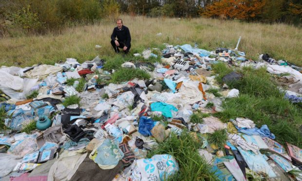 Cllr Bill Duff, with some of the fly tipping, next to the former Guthries Garage in Montrose.