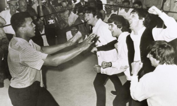 The Beatles John Lennon, George Harrison, Paul McCartney, and Ringo Starr pretend to gang up on boxer Cassius Clay (aka Muhammad Ali) on a visit during their first US tour in 1964