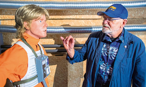 Actor Angus MacInnes, who played the role of Gold leader Jon 'Dutch' Vander in Star Wars, stands in front of the silicone replica of one of the main characters of the Star Wars films, Luke Skywalker.