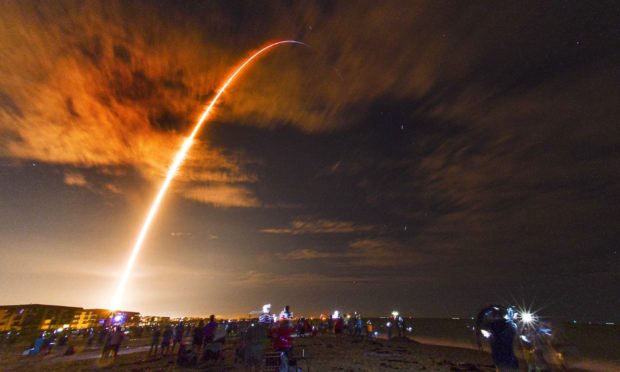 Crowds on the beach in Cape Canaveral, Fla., watch the launch of the SpaceX Falcon 9 Crew Dragon.